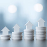 Stacks of coins with upward arrows symbolising rising UK house prices.