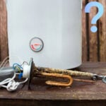 Corroded water heater element beside boiler with temperature gauge