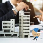 Model buildings with business professionals discussing rising property costs and management reform