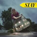 Woman holding a house symbolizing tenants staying put amid rising rents