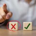 Wooden blocks with red cross and green check mark symbolizing correct and incorrect housing policy decisions