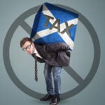Man struggling under a heavy tax burden symbolised by a Scotland-themed block, illustrating concerns over a potential landlord tax hike.