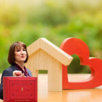 Rachel Reeves holding a red ministerial-style briefcase beside wooden house and heart shapes, symbolising housing policy impacts