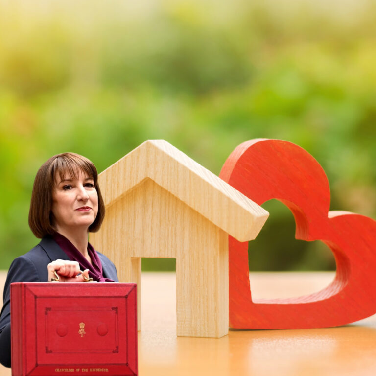 Rachel Reeves holding a red ministerial-style briefcase beside wooden house and heart shapes, symbolising housing policy impacts
