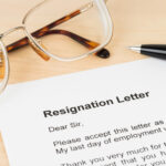Resignation letter on desk beside glasses and pen symbolizing councillor’s resignation.