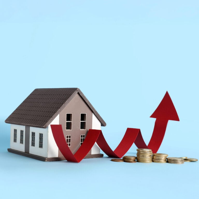 Model house beside stacked coins and rising red arrow symbolizing UK house price growth.