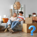 Couple sitting on a sofa with moving boxes and a cracked divide, representing tenancy changes and HMO risk