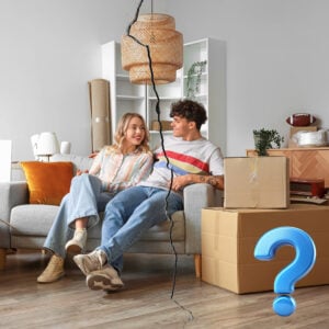 Couple sitting on a sofa with moving boxes and a cracked divide, representing tenancy changes and HMO risk