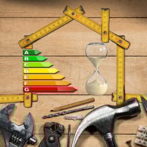 Energy efficiency tools forming a house shape with EPC rating scale and hourglass on wooden background