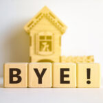 Wooden letter blocks spelling “BYE!” in front of a small model house, symbolising landlords leaving the rental market