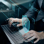 Hands typing on a laptop with digital privacy and security graphics overlaying the screen