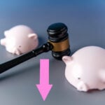 gavel striking between two piggy banks symbolising falling tenancy deposit disputes