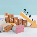 Wooden houses and percentage markers next to a downward arrow illustrating falling rents in England.