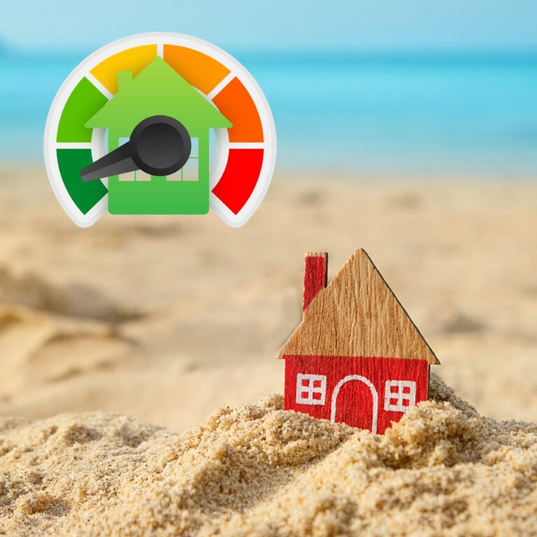 Toy house in sand with energy efficiency rating icon representing EPC rules for holiday lets