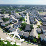 Aerial view of a suburban housing estate with a plane flying overhead, symbolising overseas property ownership