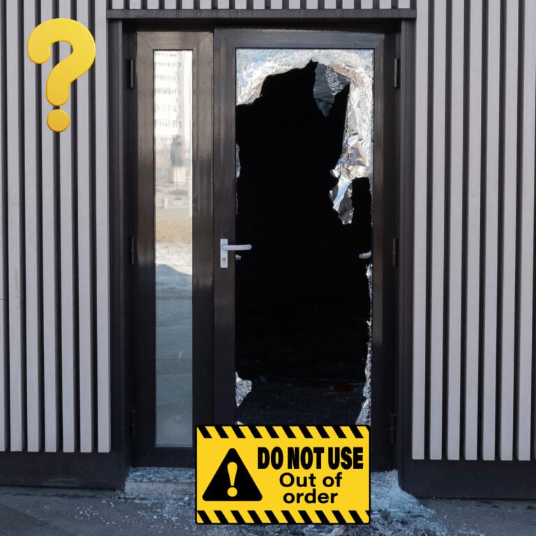 Broken communal front door of a block of flats after forced police entry, boarded and unsafe for residents