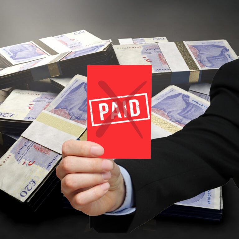 Red crossed “paid” card held over stacks of cash symbolising unpaid compensation ordered by The Property Ombudsman