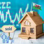 Wooden model house with a sold sign and Welsh flag, representing housing policy and empty homes in Wales