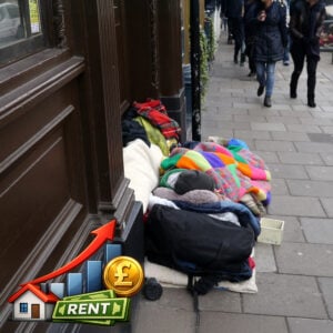 Homeless person sleeping in blankets on a city pavement as pedestrians walk past, highlighting the impact of unaffordable rents