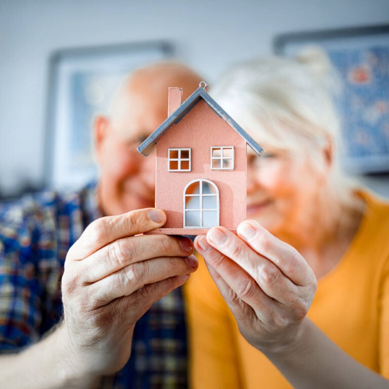 Elderly couple holding a small model house, symbolising small-scale landlords in England’s private rented sector