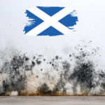 Damp and mould staining on a wall beneath a painted Scottish flag, symbolising housing standards issues in Scotland