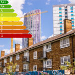 Energy efficiency rating scale over social housing buildings with cranes and apartment blocks in the background