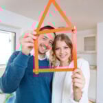 Smiling couple holding house-shaped frame symbolising positive renting experience in England