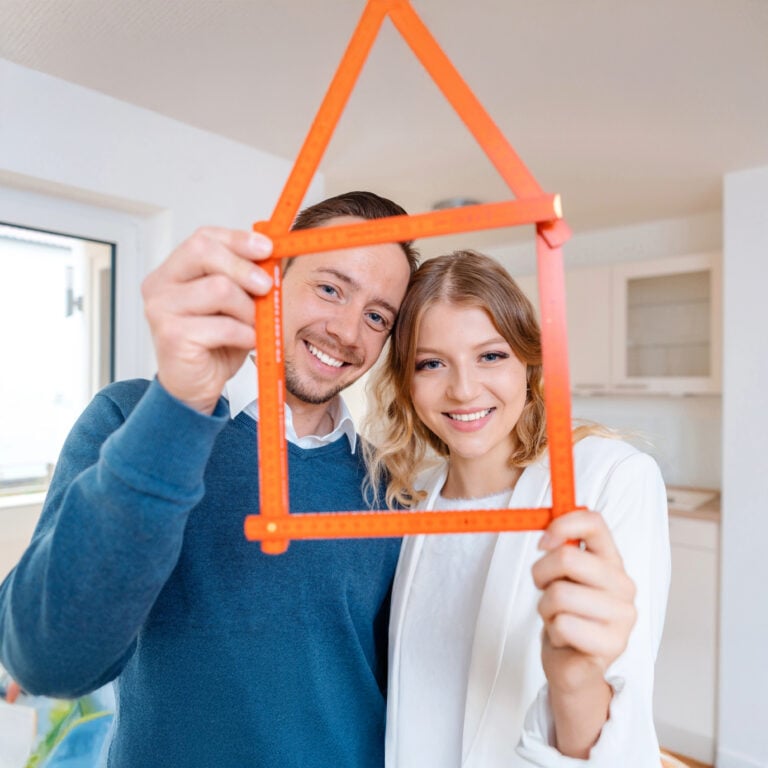 Smiling couple holding house-shaped frame symbolising positive renting experience in England