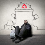 Older man sitting beneath a sketched house marked Shelter, symbolising homelessness and the housing crisis