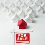 Red house model above a for sale sign symbolising rising UK home listings