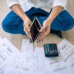 Empty wallet held above household bills and a calculator, reflecting the financial strain of rising rents