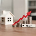 Rising rents illustrated by stacked coins and upward red arrow beside a model house