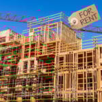 Timber-frame apartment block under construction with crane and “For Rent” sign illustrating growth in build-to-rent housing