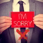 Businessperson holding “I’m Sorry” sign highlighting need for stronger apologies in social housing complaints