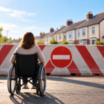 Wheelchair user facing a road barrier, highlighting accessibility challenges and the need for home adaptations.